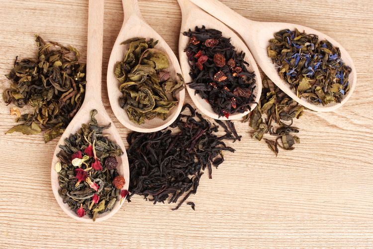 Různé druhy zeleného a černého čaje na dřevěných lžících