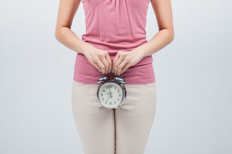 Zpožděný menstruace - mladá žena s hodinami před klínem